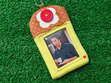 Load image into Gallery viewer, a custom felt ID badge holder designed like a dessert, featuring a yellow pudding or flan base, a brown top with a red button detail, and a photo slot in the center displaying a man. the item is laid flat on a green artificial turf background.