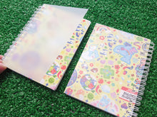 Load image into Gallery viewer, two spiral-bound notebooks showing the front and back of a colorful pattern, placed on a green grass-like surface. the photo demonstrates a frosted plastic sheet on the front and back of the book.